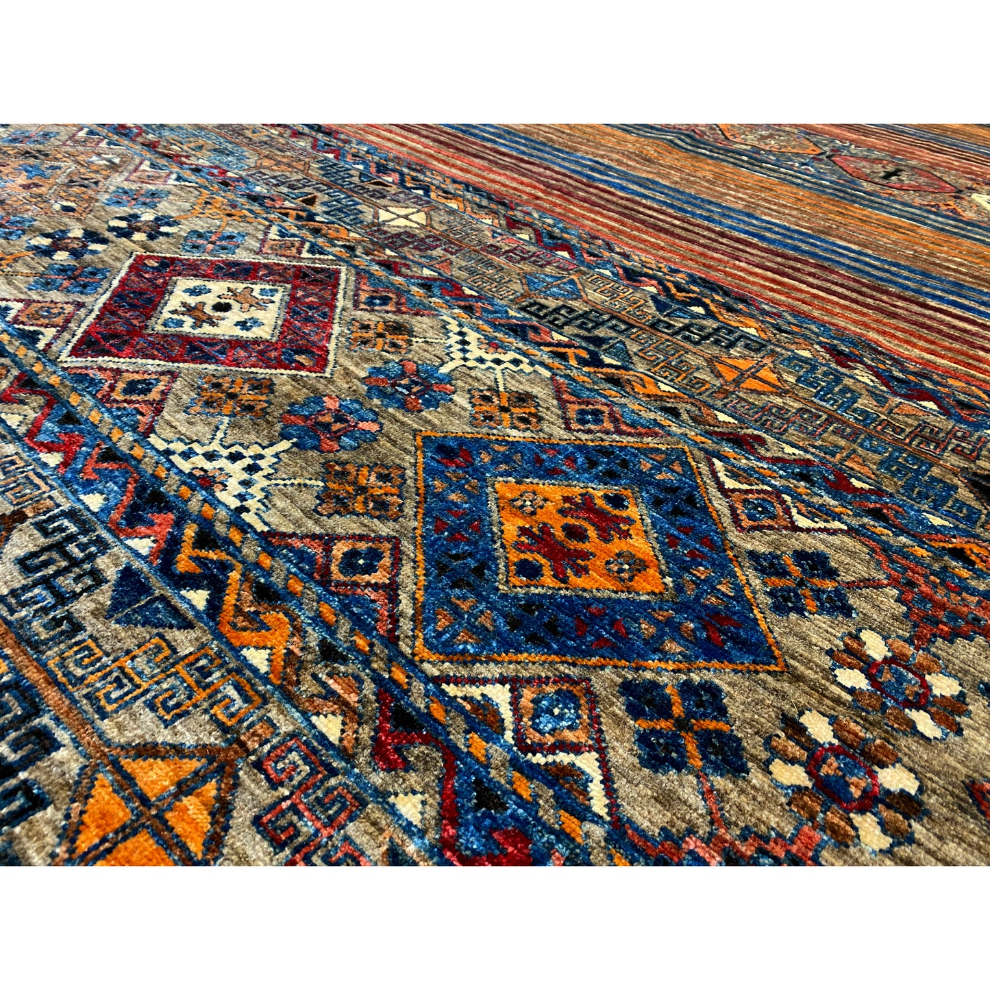 Nahansicht vom bunten Teppichmuster mit Quadraten, Linien und Ornamente in Blau, Rot und Beige.