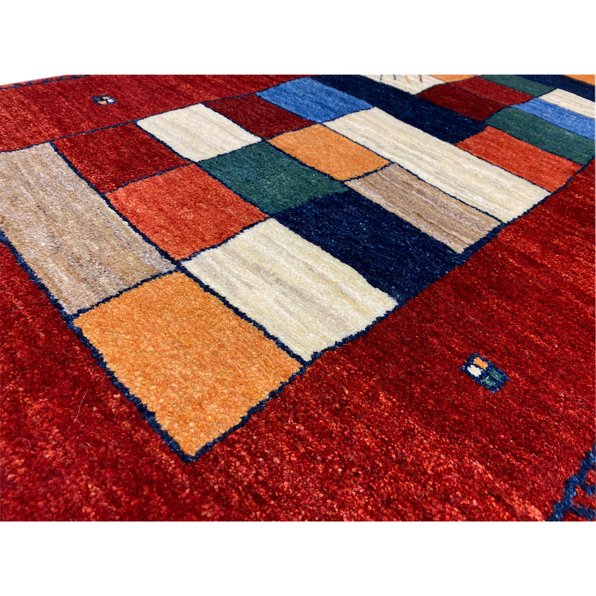 Nahaufnahme: roter Gabbeh-Teppichläufer mit Patchwork-Quadraten in Orange, Blau, Beige