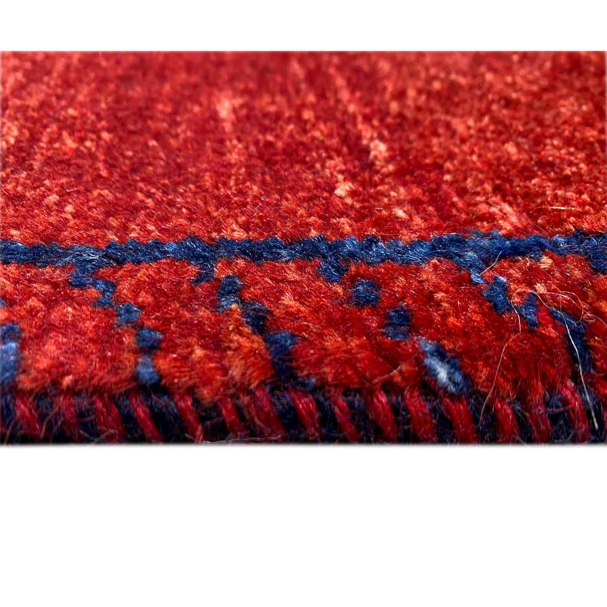 Detail: roter Gabbeh-Teppichläufer mit blauer Zierkante und Fransen
