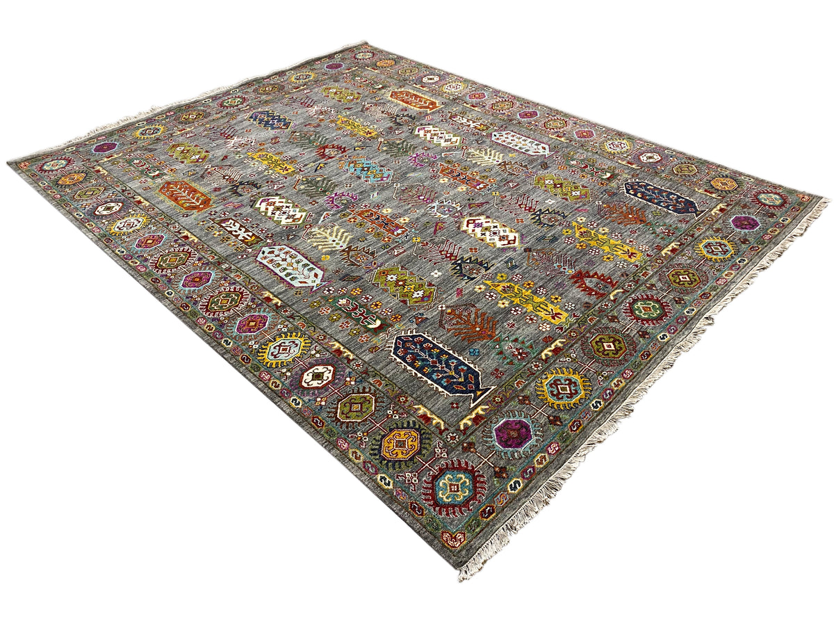Teppich in Grau mit bunten Medaillons, geometrischer Bordüre und Fransen.