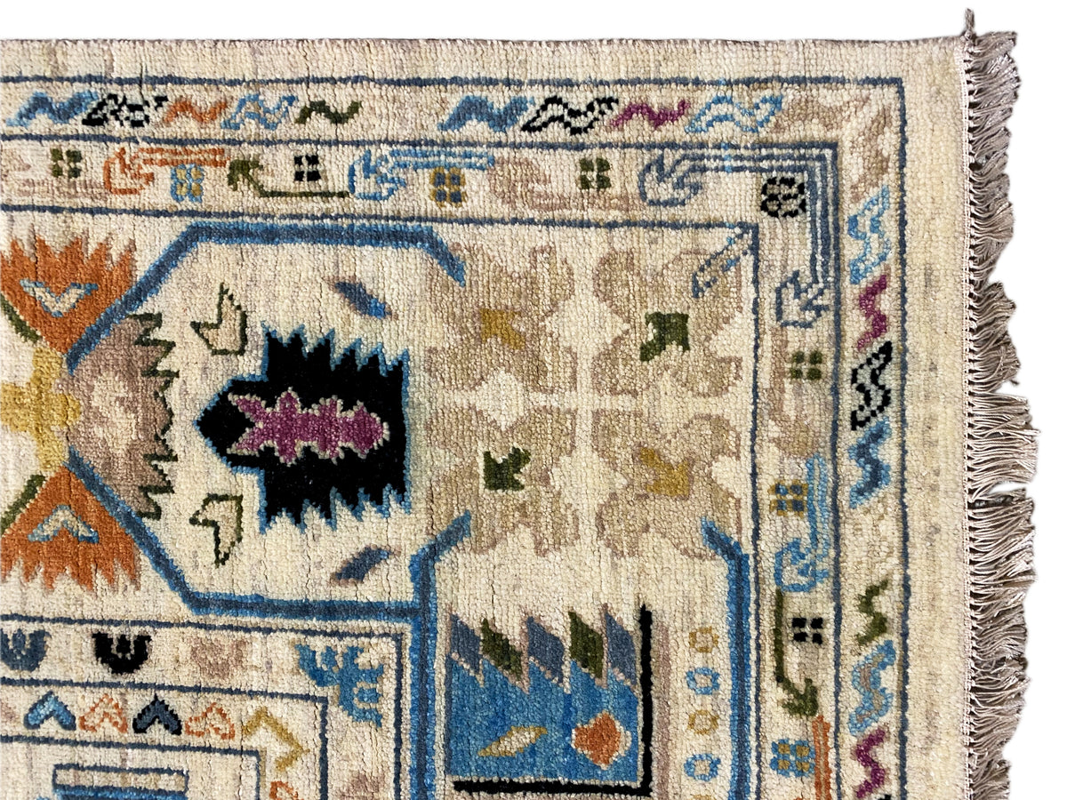 Nahansicht vom Indo-afghanischen Teppich: blau-graue Ornamentik und Fransen am Rand