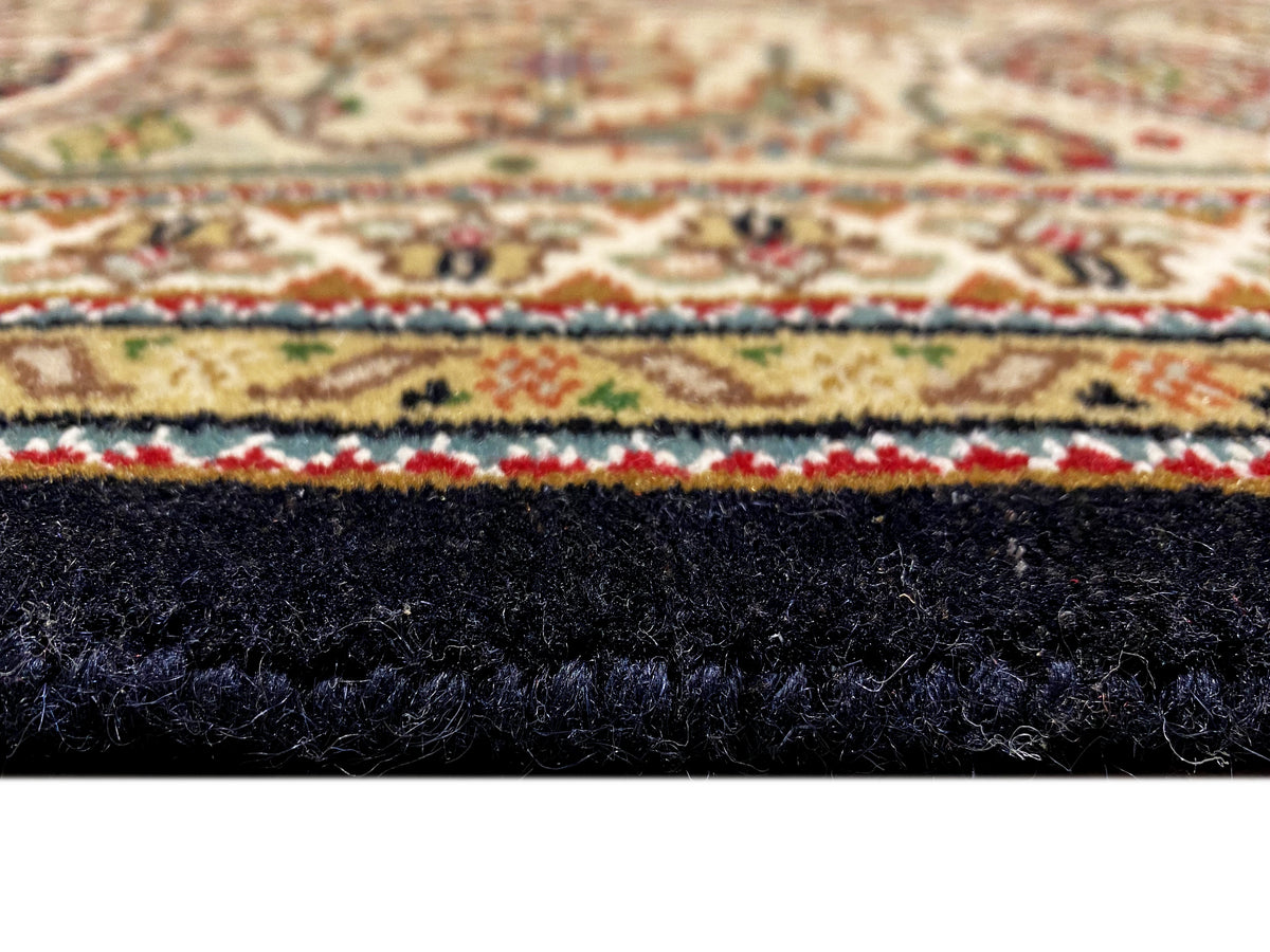 Indo Tabriz-Teppich: Nahaufnahme der Teppichkante mit dunklem Flor und mehrfarbiger Einfassung