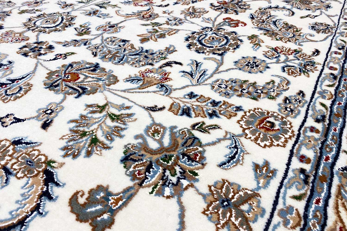 Nahaufnahme: beiger Orientteppich mit detailliertem Blumen-Ornament in Blau und Braun