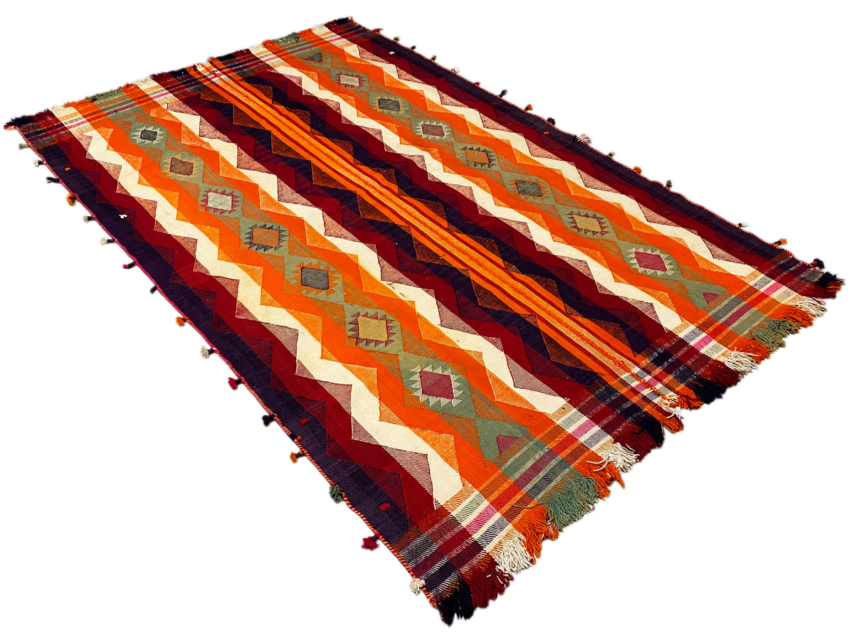 Jajim-Teppich schräg von oben, Zickzack- und Streifenmuster in Orange und Dunkelblau