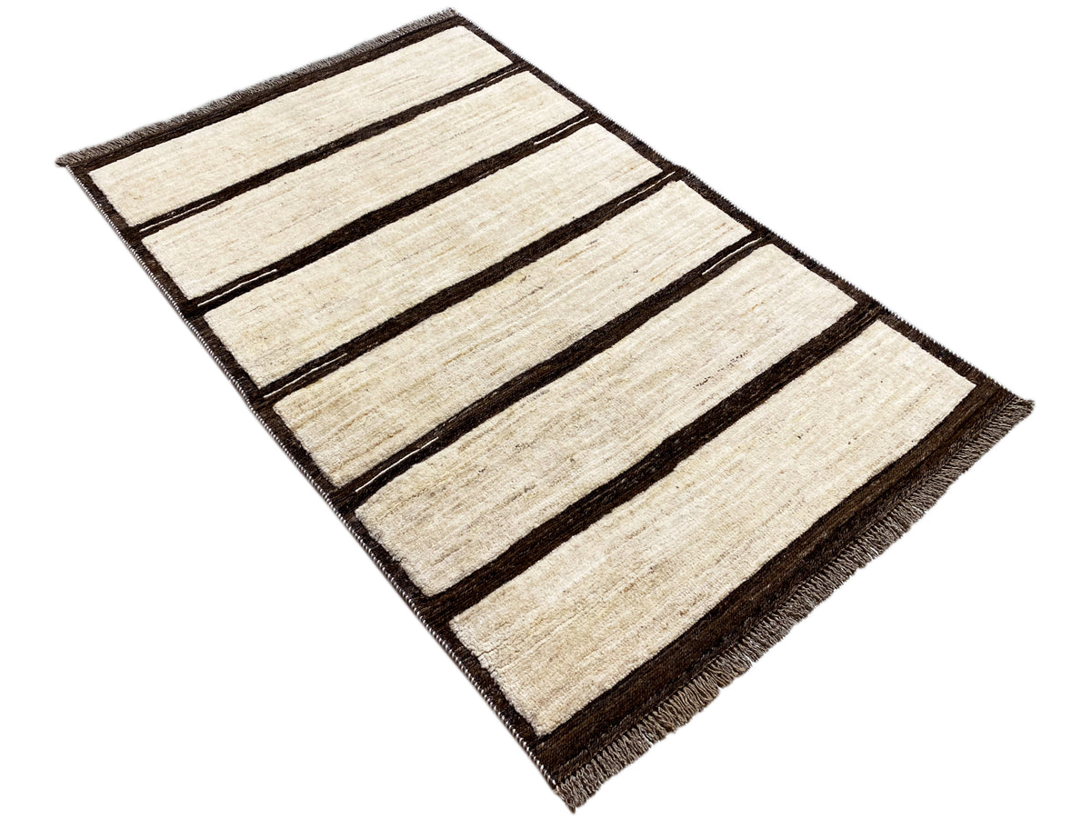 Rechteckiger Kelim-Teppich in Beige mit dunklen Streifen, diagonal fotografiert, mit Fransen.