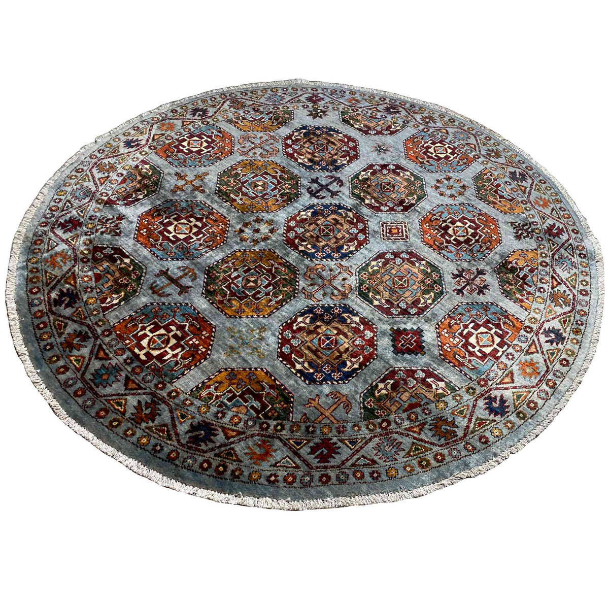 Runder Teppich: geometrische Hexagon-Ornamente in Orange, Rot und Blau auf hellgrauem Grund