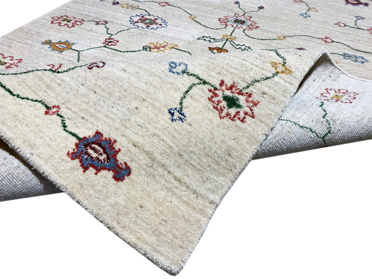 Teppich in Creme mit buntem Muster, sichtbare Kante und Floransatz.