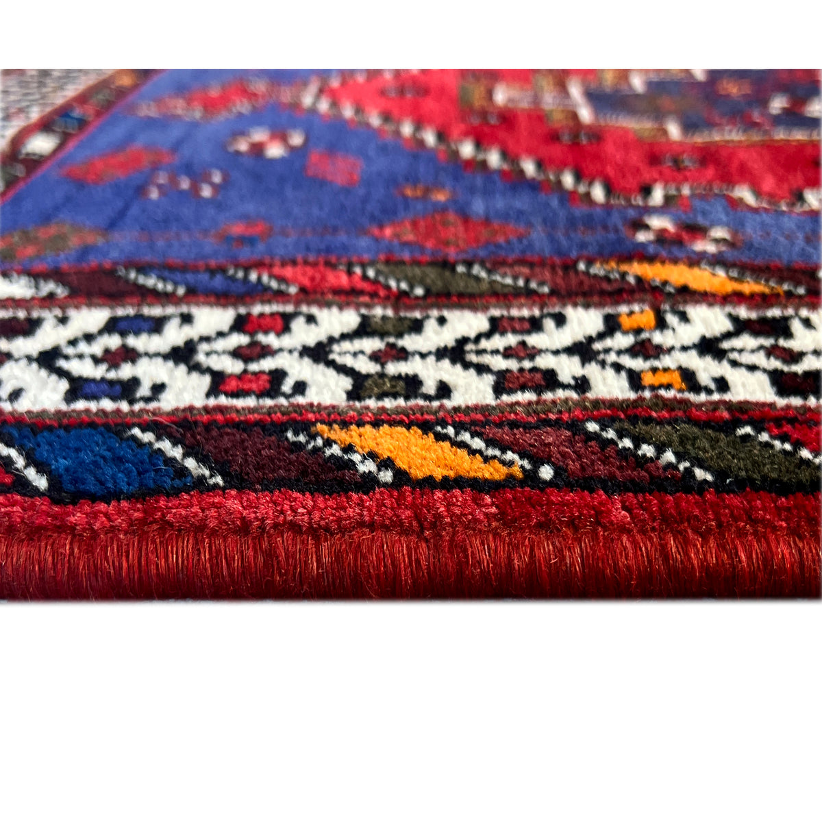 Teppichläufer mit rotem Fransenrand und geometrischem Muster in Blau und Rot