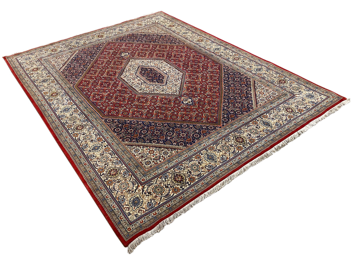 Teppich mit rotem Mittelmotiv, hellen Zierlinien und breiter ornamental gemusterter Einfassung
