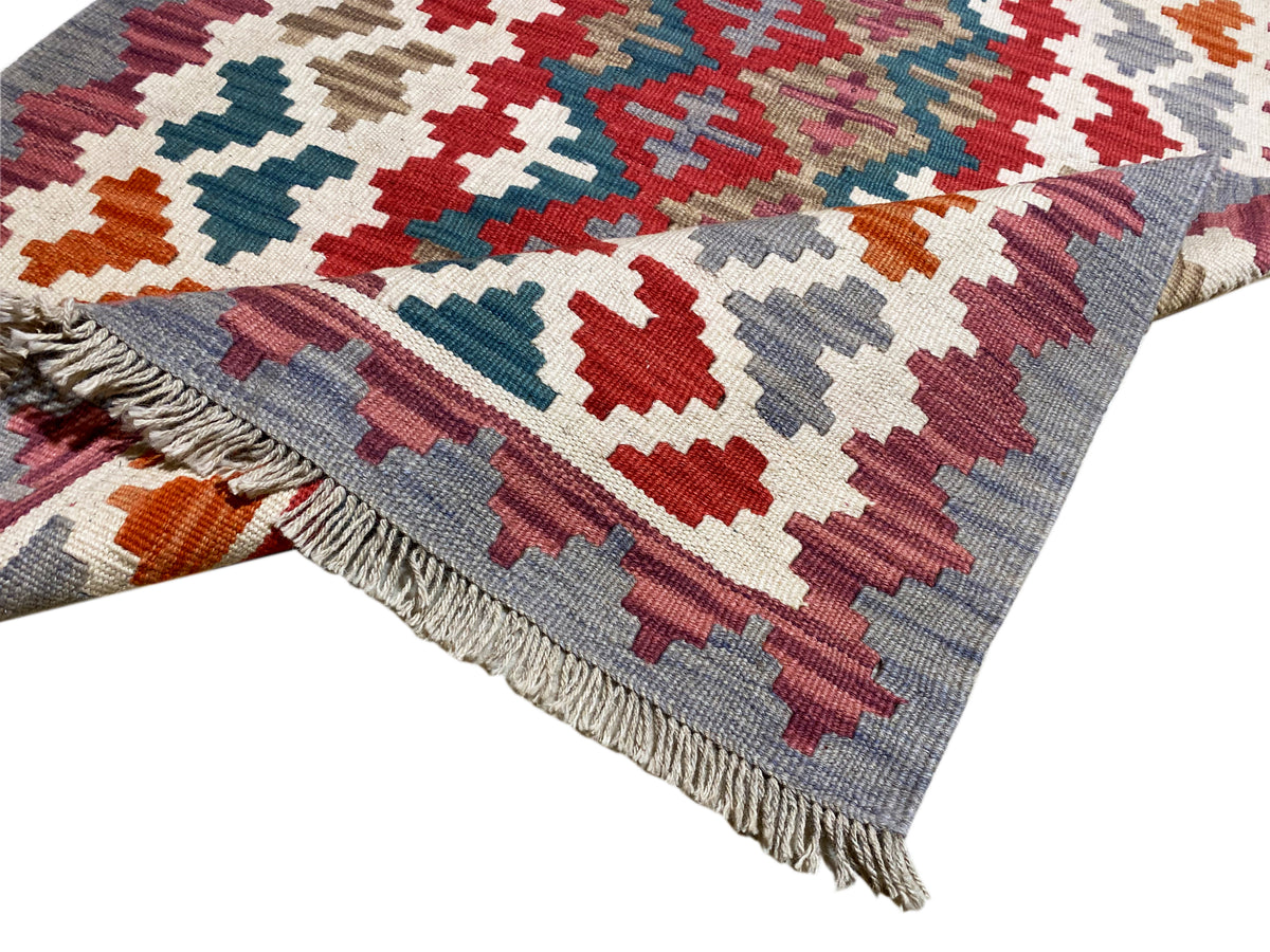 Kelim Teppich mit geometrischem Allover-Muster und Fransen am Rand, mehrfarbig