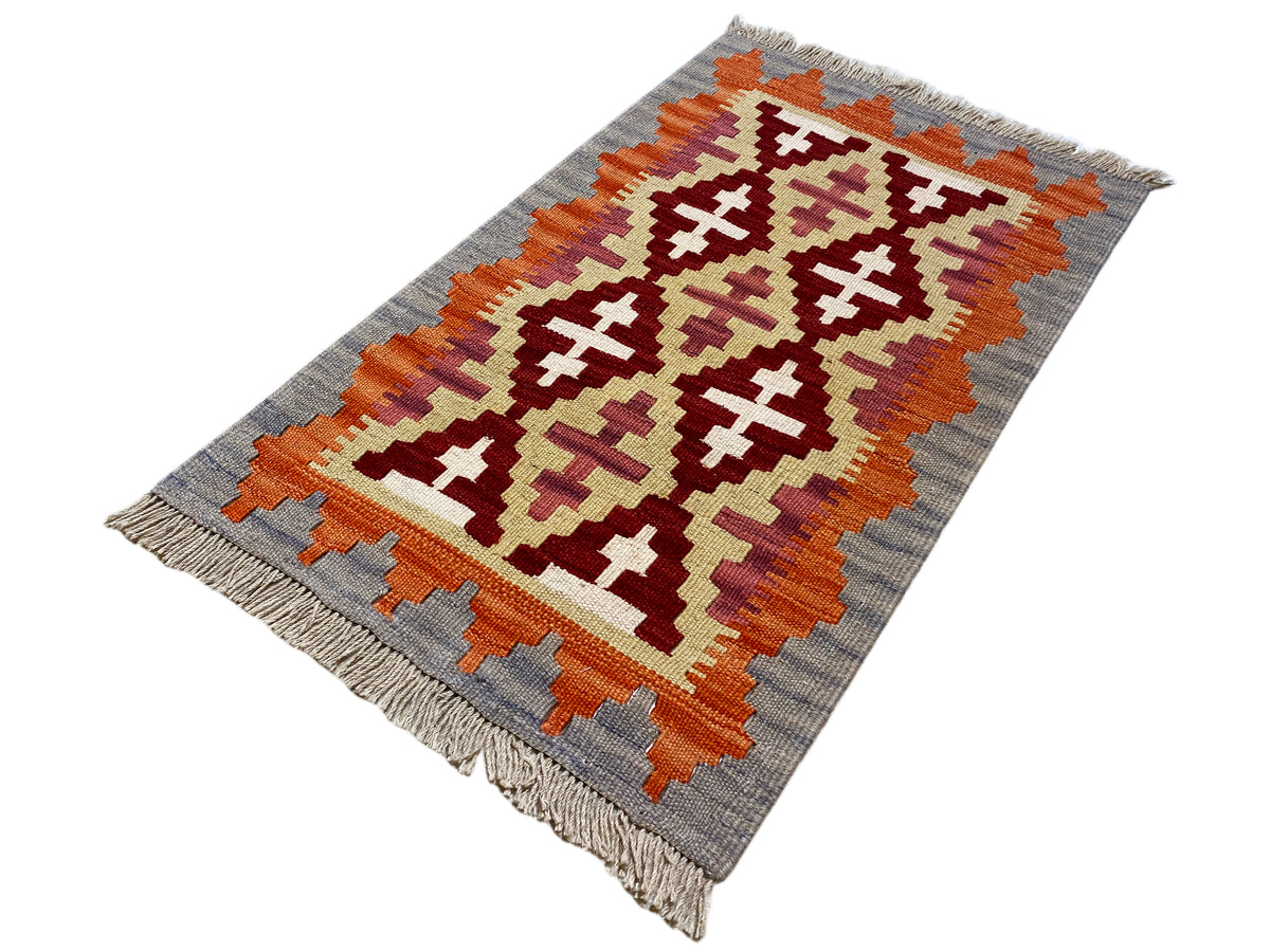 Kelim-Teppich im Querformat mit Kreuz- und Rautenmustern in Orange, Creme und Grau