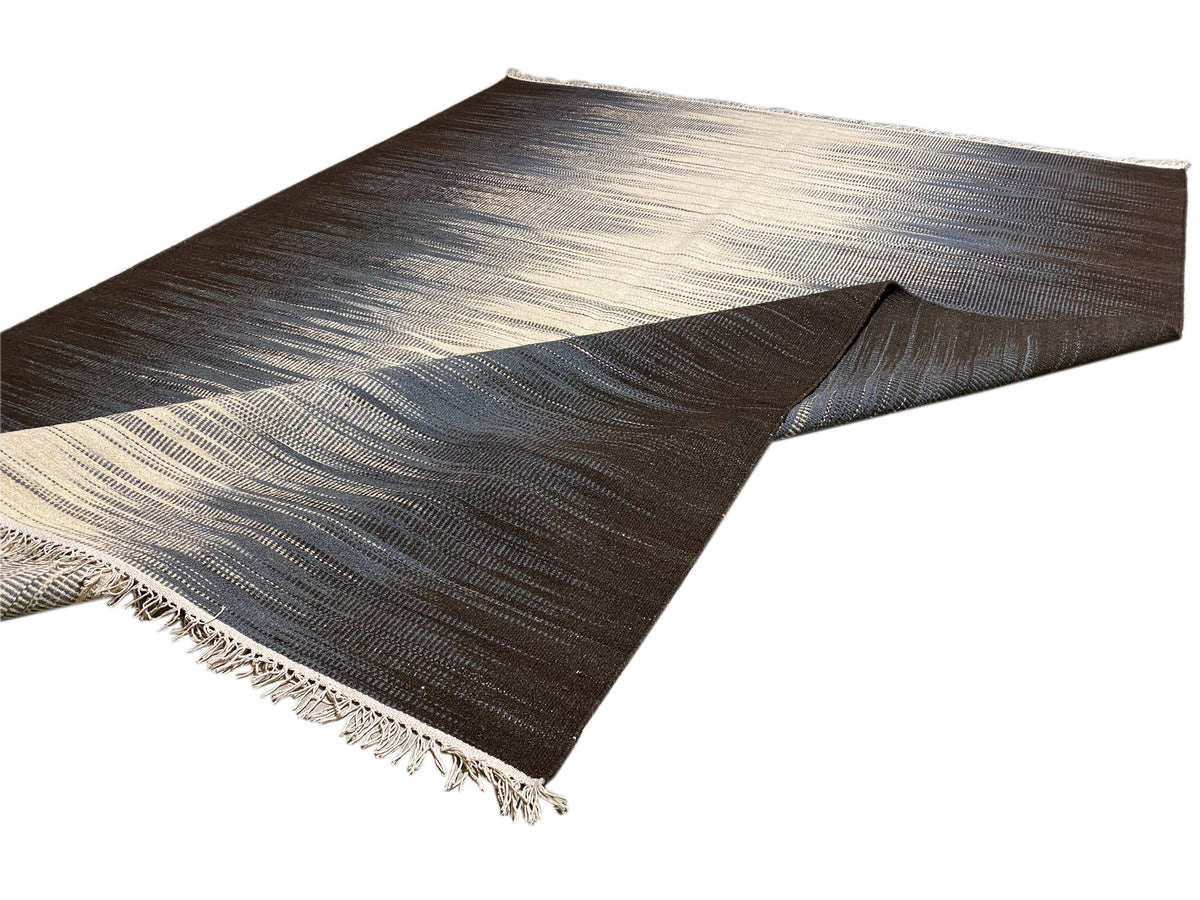 Kelim-Teppich 170x240 cm von der Seite: dunkle Fläche mit hellen Streifen und Fransen
