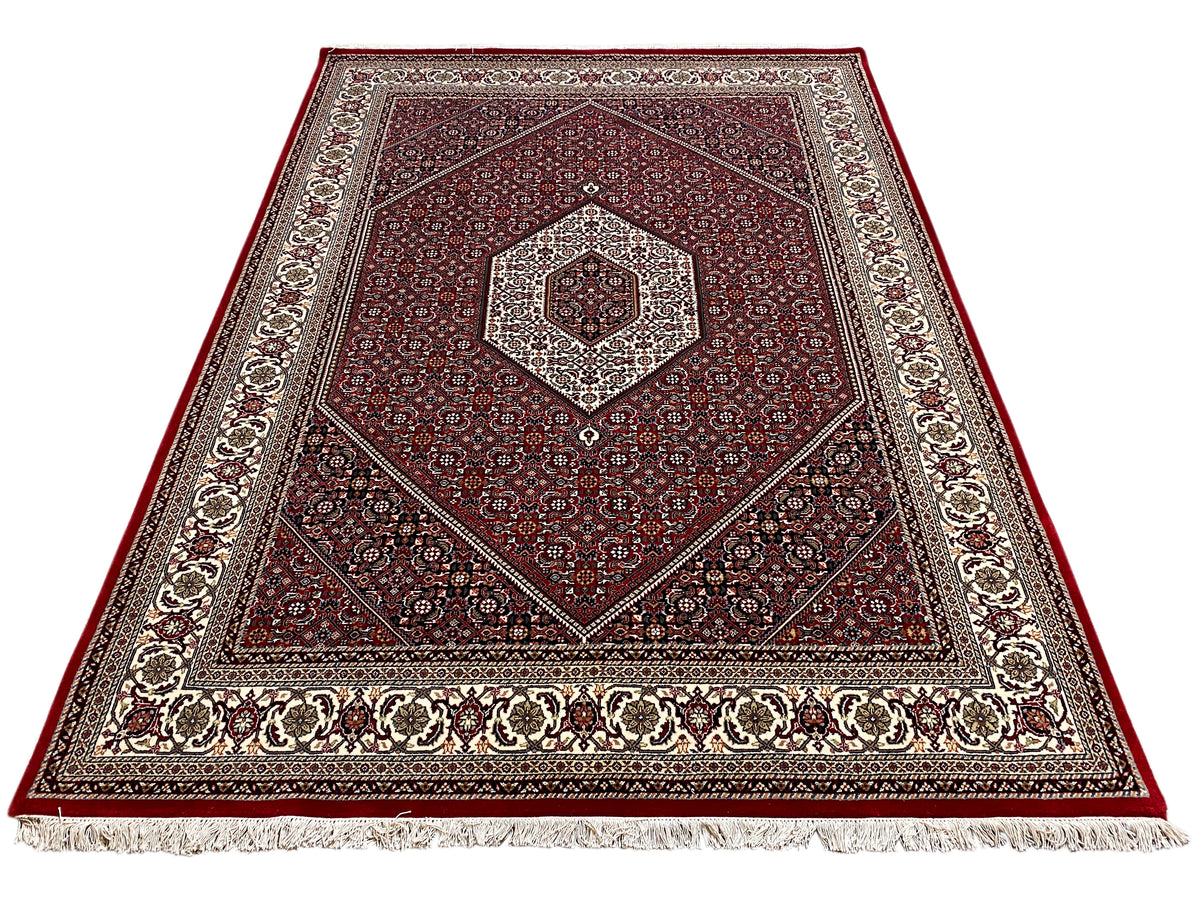 Roter Teppich mit zentralem Medaillon, symmetrischem Ornament und Fransen am Rand