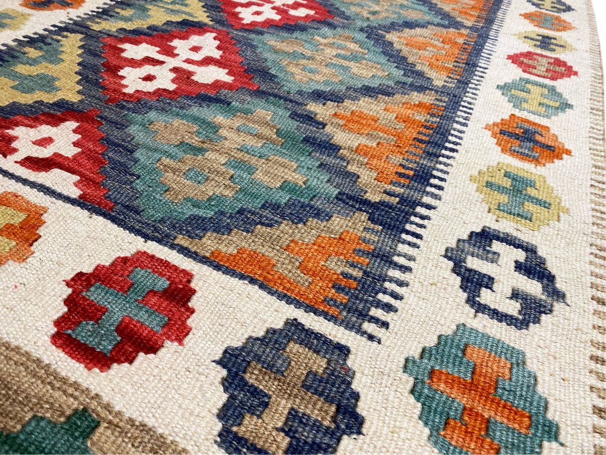 Nahaufnahme Kelim-Teppich: Kreuz- und Rautenmotive, bunte Farbfelder an der Kante