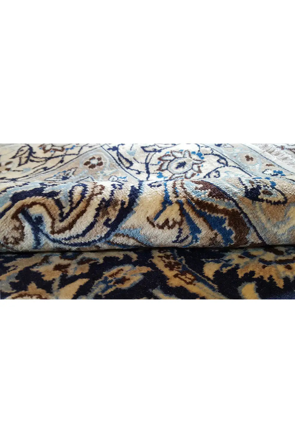 Detailansicht: ornamentales Teppichmuster in Blau und Beige, mit sichtbarer Florstruktur.