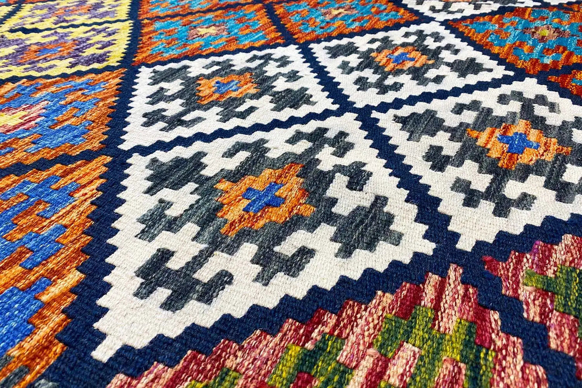 Kelim-Teppich mit geometrischem Muster, Nahaufnahme in Blau, Weiß und Orange.
