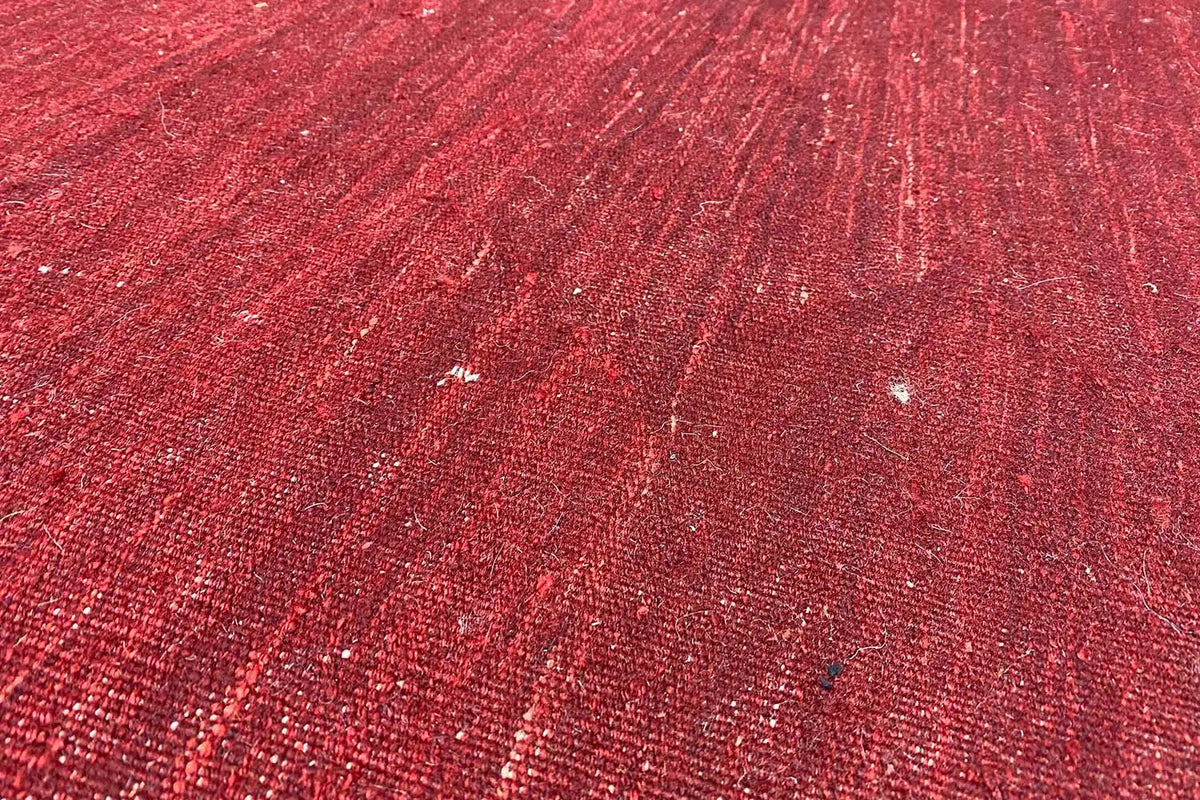 Roter Kilim-Teppich Detailaufnahme der Oberfläche mit schimmernden Fasern und dezenter Zeichnung