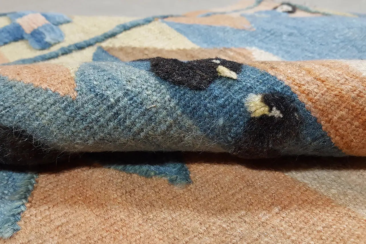 Gewebter Teppich: Nahdetail der Kante mit hellblauen und beigen Farbfeldern