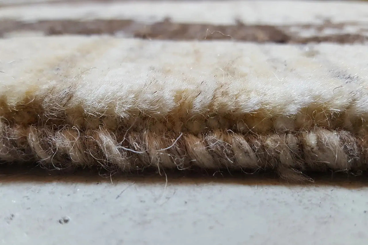 Teppichfranse am Rand, dichter Flor in hellem Beige mit braunen Bereichen