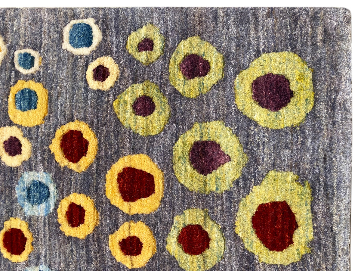 Gabbeh-Luri-Teppich Nahaufnahme: graue Wolle mit gelben, roten und blauen Kreisringen