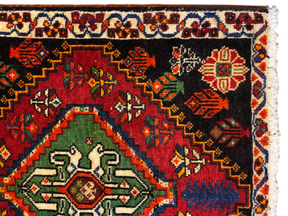 Poshti-Teppich Nahansicht: schwarzer Teppich mit grünem Medaillon und bunten Ornamenten