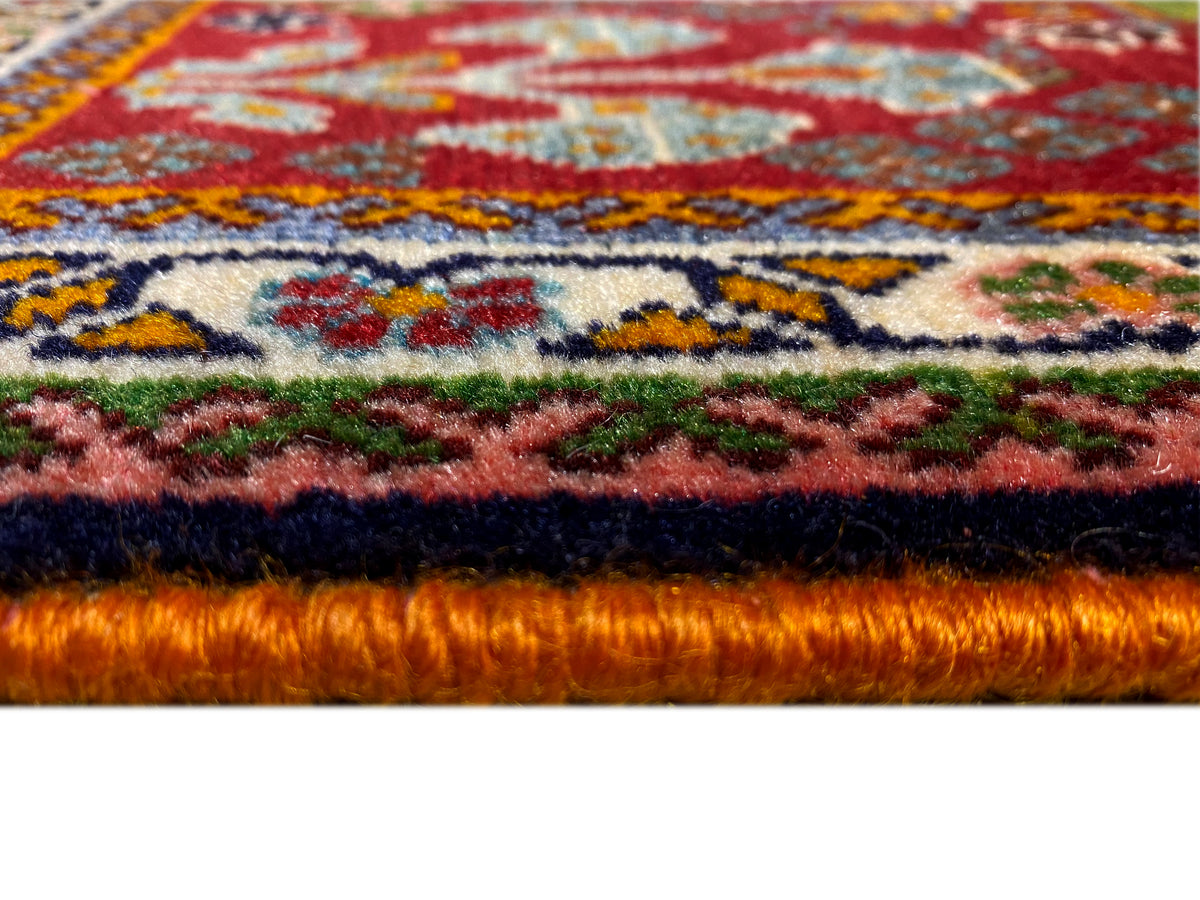 Teppichkante im Detail: dichter Flor mit rotem Untergrund und farbigen Ornamenten