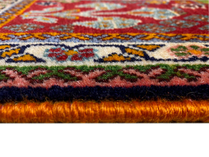 Teppichkante im Detail: dichter Flor mit rotem Untergrund und farbigen Ornamenten