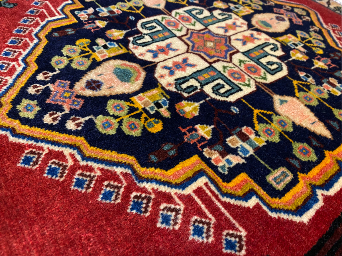 Poshti-Teppich mit dunkelblauem Zentrum, roten Rändern und bunten geometrischen Motiven