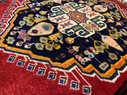 Poshti-Teppich mit dunkelblauem Zentrum, roten Rändern und bunten geometrischen Motiven