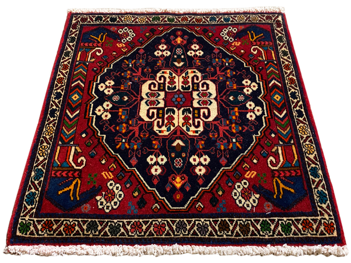 Teppich im Quadratformat mit zentralem Medaillon, rot-blaue Ornamentik und kurze Fransen