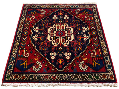 Teppich im Quadratformat mit zentralem Medaillon, rot-blaue Ornamentik und kurze Fransen
