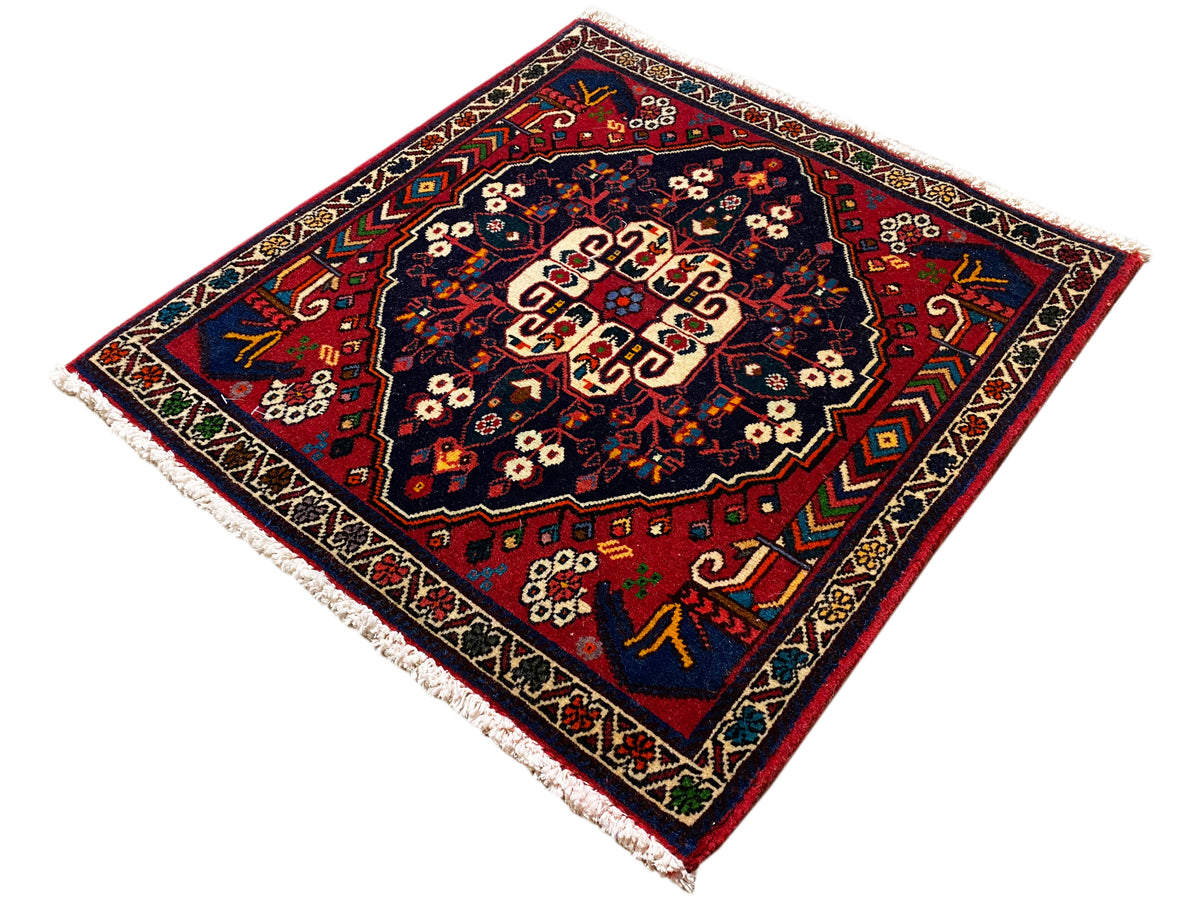 Quadratischer Teppich mit dekorativem Rand, rot-blaues Muster und cremefarbener Bildmitte