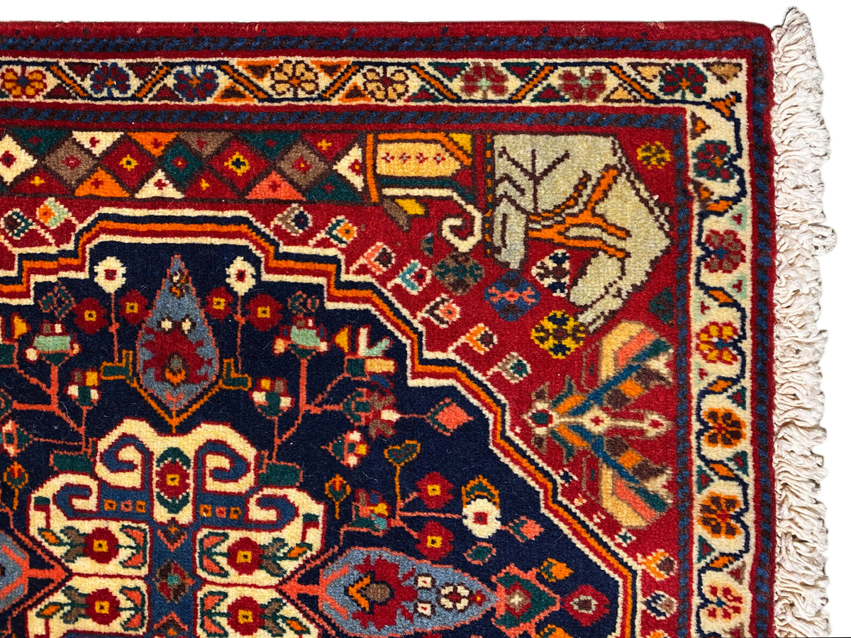 Nahaufnahme vom Teppichrand mit blauem Ornamentfeld, roten Details und Fransen