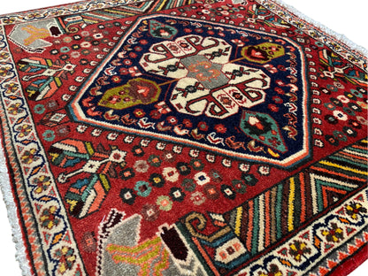 Orientalischer Teppich schräg fotografiert: rotes Muster, dunkles Medaillon und mehrfarbige Einfassungen