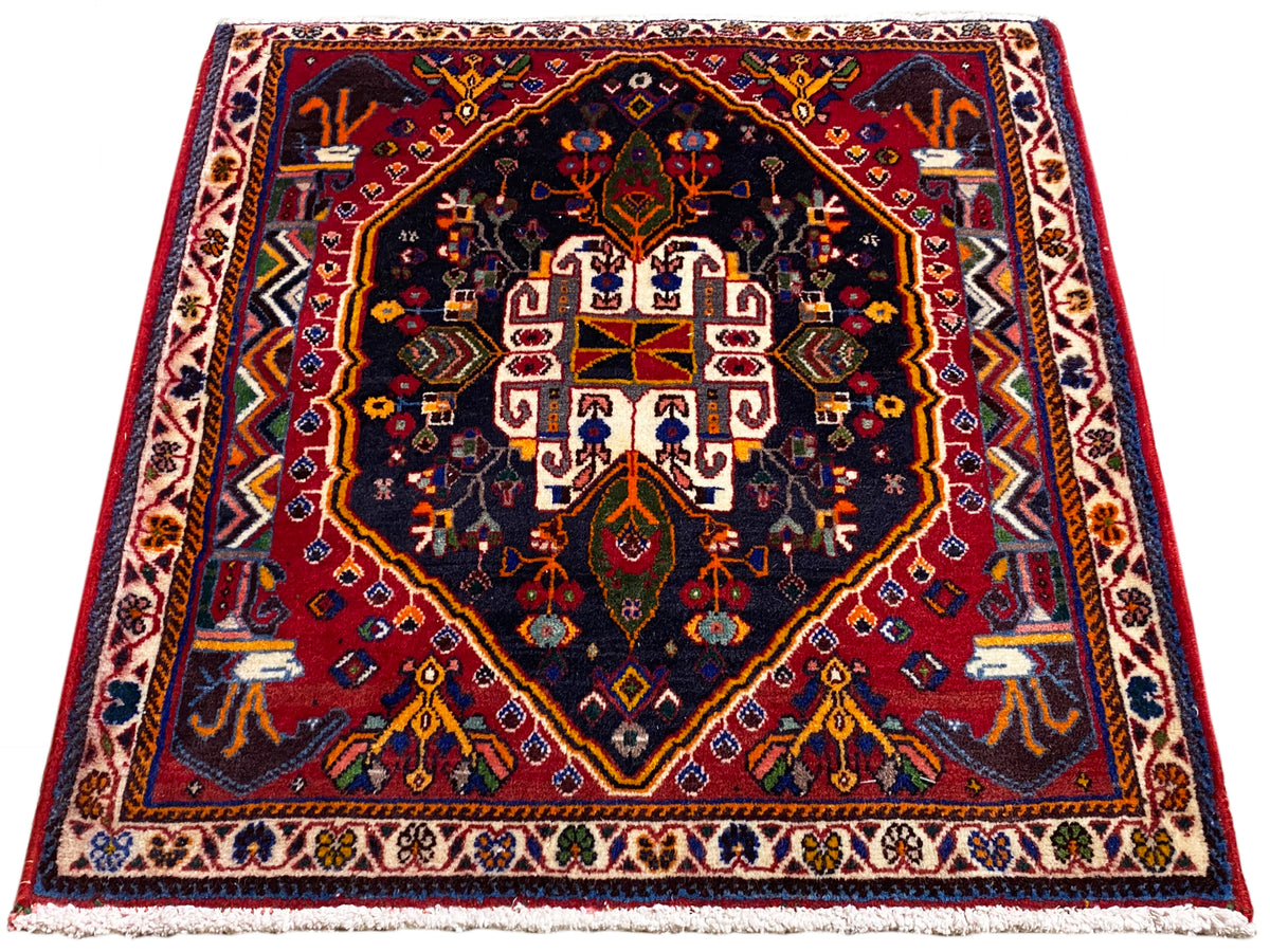 Teppich 70x67 cm mit dunkelblauem Grund, rotem Rahmen und symmetrischem Medaillonmuster