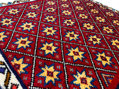 Nahaufnahme vom Teppich: rotes Rautenfeld mit gelben und blauen Sternen